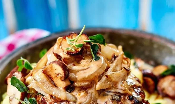 Frikadellen mit Champignons in Pfefferrahmsoße auf einem Teller serviert