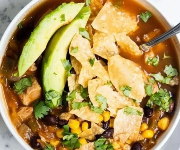 Schüssel mit One Pot Chicken Tortilla Soup mit frischen Zutaten