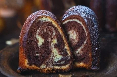 Marmor-Lebkuchen-Gugelhupf auf einem Teller, dekoriert mit Puderzucker.