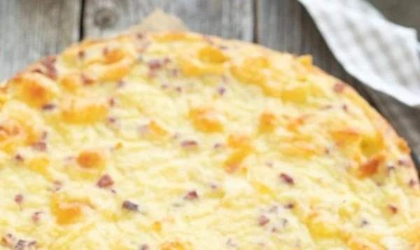 Zwiebelkuchen ohne Boden auf einem weißen Teller, frisch gebacken.